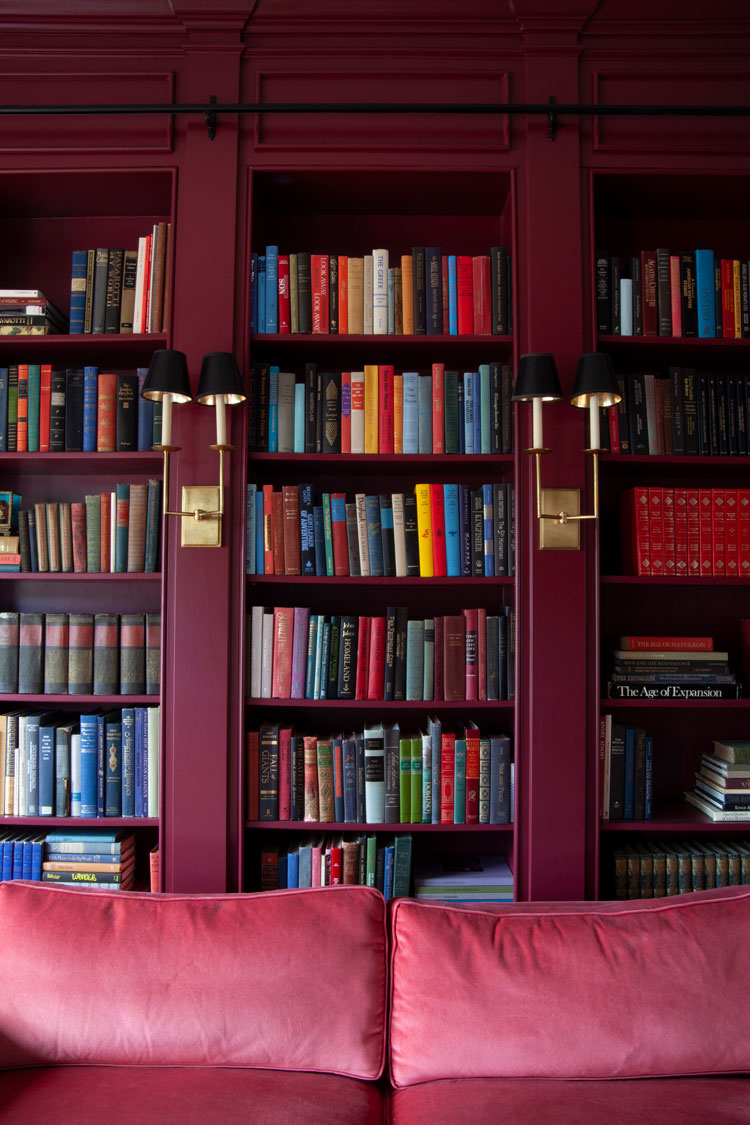 Moody 2023 interior design trends via the Makerista - burgundy bookshelves with individual sconces